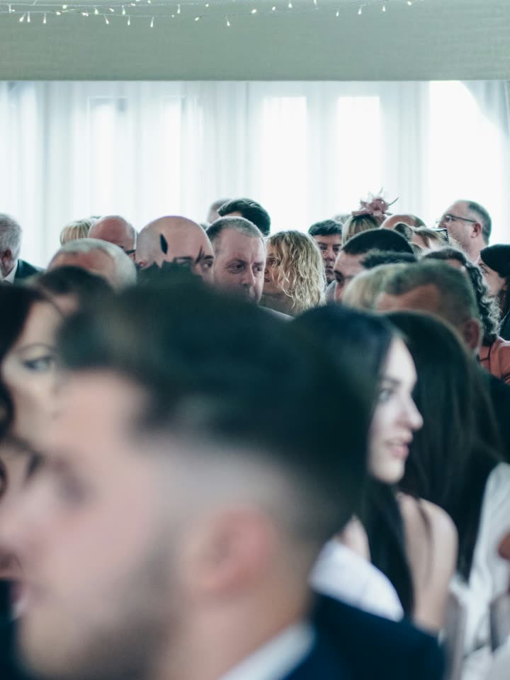 Photo of a crowded ceremony room with the focus falling between rows of guests