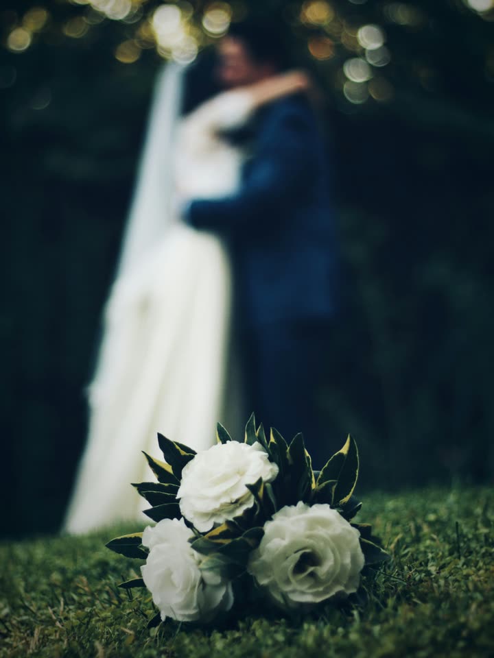 Photo of a bouquet in sharp focus with the couple blurred in the background